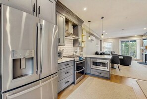 Una cucina moderna con elettrodomestici in acciaio inossidabile, un'isola centrale e un'area pranzo con sedie.