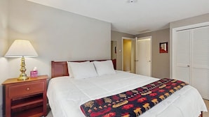 Ein Hotelzimmer mit Bett, Nachttischlampe, Nachttisch, Tür und Schrank.