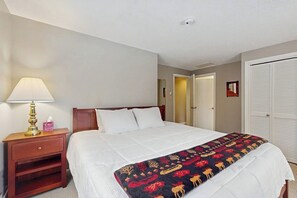 Ein Hotelzimmer mit Bett, Nachttischlampe, Nachttisch, Tür und Schrank.