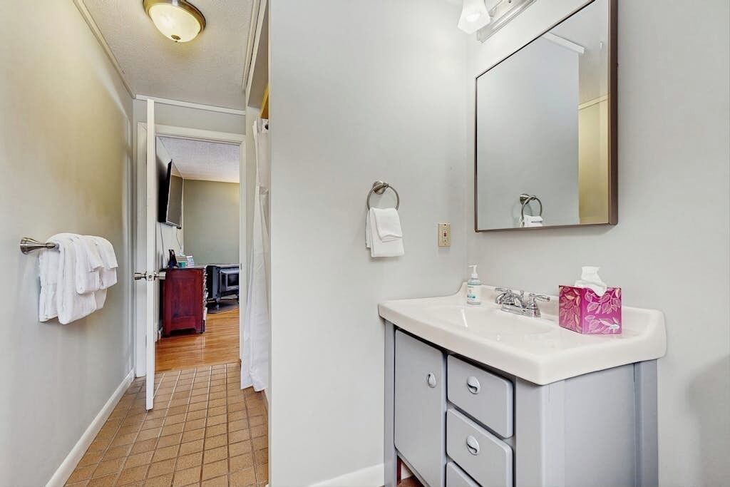 A bathroom with a white sink, a mirror, a towel rack, and a toilet.
