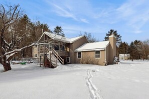A two-story house with a wooden exterior, a covered porch, and a staircase leading to the upper floor. - White Mountain home w/ yard near skiing, hiking & tubing (Campton)