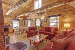 Ein rustikales Blockhaus-Interieur mit Essbereich, einer Couch und einem Kamin.