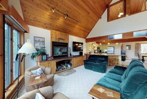 A spacious living area with a fireplace, television, and kitchen area. - Bright, Open Home with Wraparound Deck & Mountain Views - 2 Miles to Skiing (Ludlow)