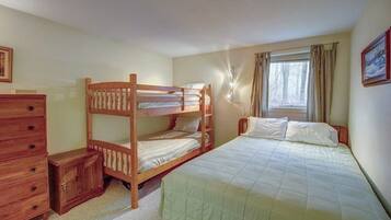 A bunk bed room with a dresser, a small cabinet, and a window with curtains.