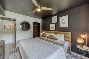 Ein Schlafzimmer mit einem Bett, Nachttischlampen, einem Deckenventilator und Kunstwerken an den Wänden.