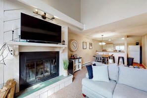 A living room with a fireplace, television, and a sofa. - Two Okemo condos - ski-in/ski-out - pool, fast WiFi, washer/dryer (Ludlow)