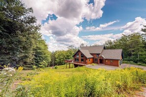 A lodge with a covered porch, surrounded by lush greenery and a clear sky. - Mountain-view house with hot tub, AC & amazing views, near Okemo Resort & skiing (Ludlow)
