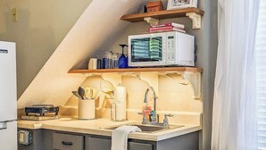 Una cocina compacta con microondas, un lavamanos y una encimera.