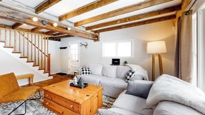 Ein Wohnzimmer mit Treppe, weißen Sofas, einem Holztisch und einer Lampe.