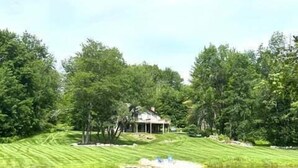 A serene pond with a gazebo and a house in the background. - Tranquil house w/ pond, 3-hole golf course, sandy beach, bbq, firepit, & trails (Londonderry)