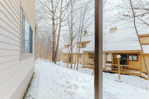 A snow-covered pathway leading to a row of wooden houses with visible windows and a covered porch. - Ski-in/out condo with a pool, tennis & fast WiFi - Sachem Trail at Okemo (Ludlow)