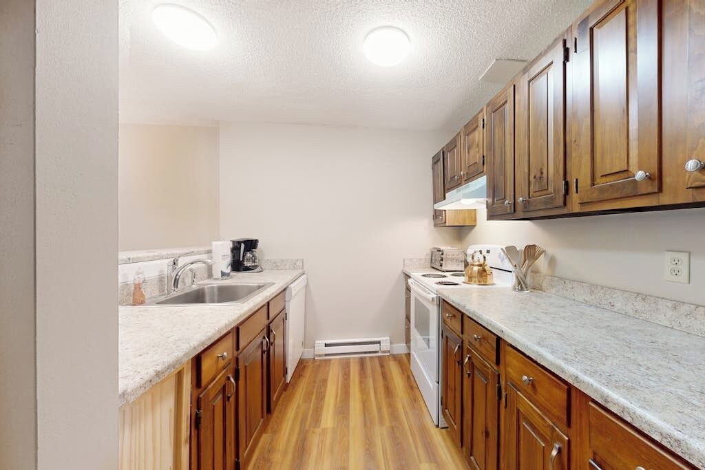 A kitchen with wooden cabinets, a granite countertop, a built-in oven, and a dishwasher.