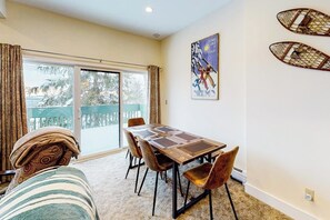 Ein Essbereich mit Tisch und Stühlen, ein großes Fenster mit Vorhängen und ein Poster an der Wand.