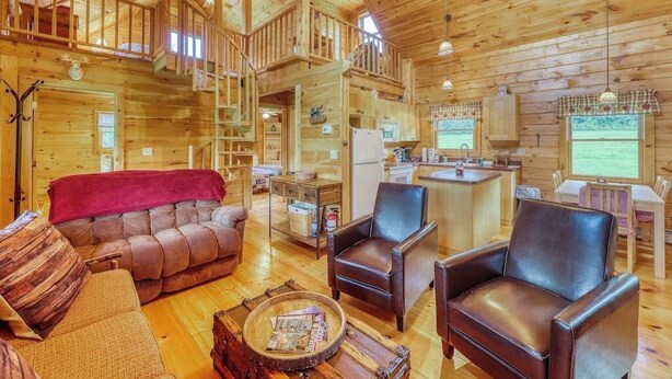 A log cabin interior with a living room, kitchen, and upper deck.