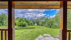 A wooden pergola structure with a view of a well-maintained grassy area and trees.