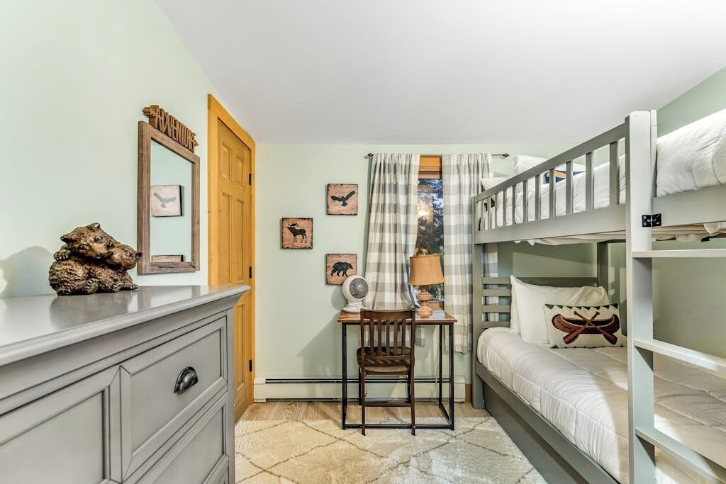 A bunk bed room with a desk, chair, and a dresser.