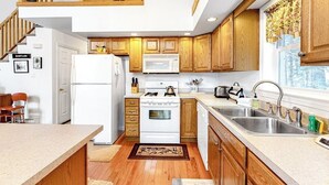 A kitchen with wooden cabinets, a white stove, a microwave, and a sink. - Perfect Home Away near Town & Skiing w/ Private Gas Grill, Large Deck (Ludlow)