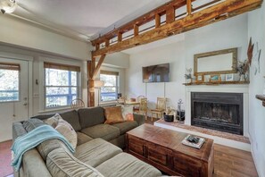 Ein Wohnzimmer mit Holzbalkendecke, Kamin, Sofa und Couchtisch.