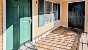 A house with a green door, a white door, and a window with blinds.