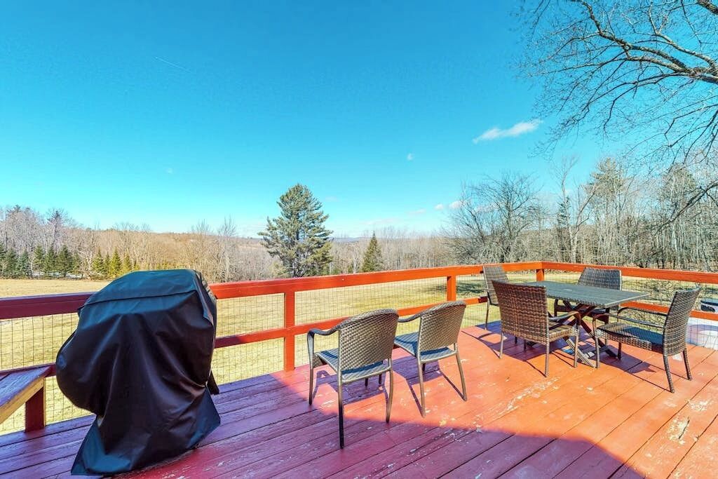 Une terrasse extérieure avec une table et des chaises, un barbecue et une vue sur une zone boisée.