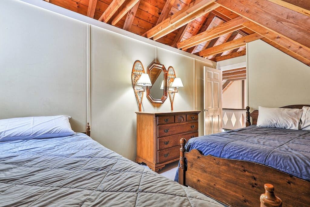 Une chambre avec deux lits, des têtes de lit en bois, une commode et un miroir agrémenté d’appliques murales.