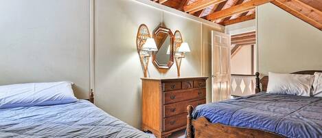 Une chambre avec deux lits, des têtes de lit en bois, une commode et un miroir agrémenté d’appliques murales.