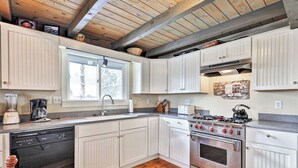 A kitchen with white cabinets, a dishwasher, a stove, and a window.