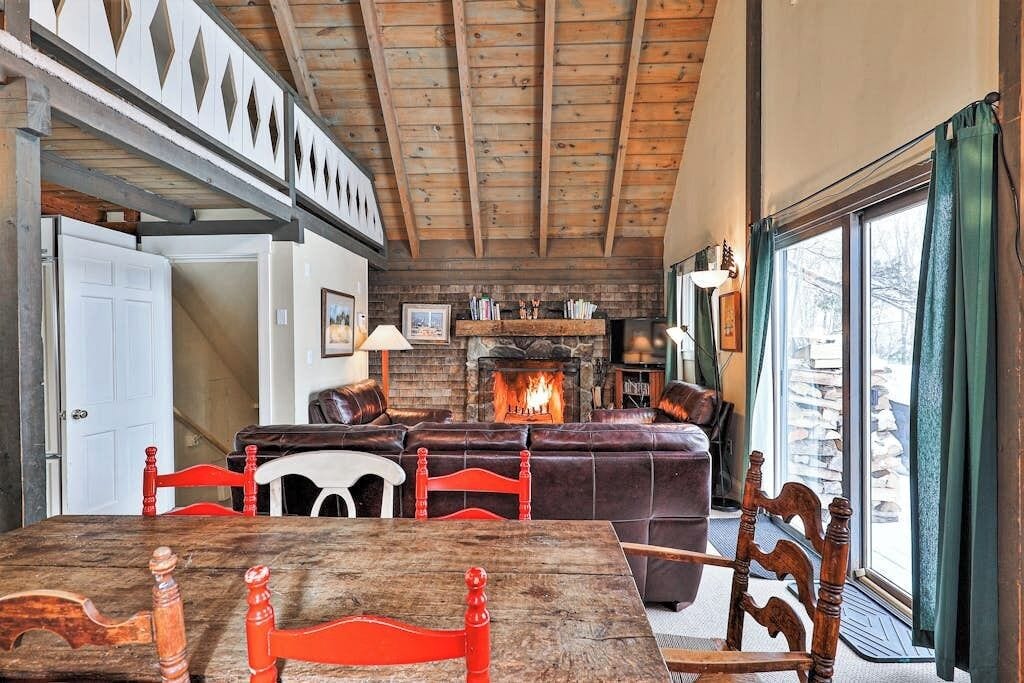 Una sala de estar acogedora con chimenea, vigas de madera en el techo y un ventanal grande.