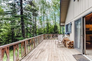 Eine Holzterrasse mit Geländer, einem Stuhl und einem Holzstapel.