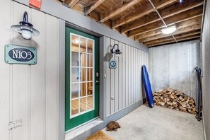 A wooden ceiling, a green door, a white wall with a number plate, and a stack of firewood. - Ski-in/out condo with a fireplace, hot tub, gym, pool, washer/dryer & cable (Ludlow)