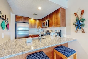 A kitchen with wooden cabinets, a stainless steel refrigerator, a microwave, a sink, and a coffee maker. - Ski-in/out condo with mountain views, fireplace, pool, & hot tub (Ludlow)