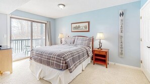 Une chambre à coucher avec un lit, deux tables de chevet avec des lampes, une fenêtre donnant sur un paysage agréable, un tableau encadré au mur et un panneau décoratif.