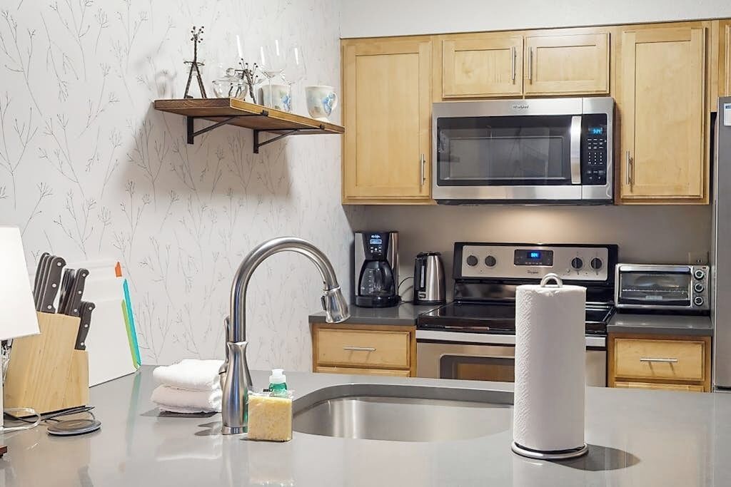 Een moderne keuken met roestvrijstalen apparatuur, houten keukenkastjes en een inbouwoven.