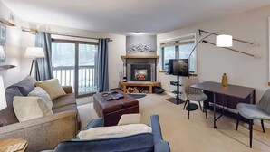 Una sala de estar con chimenea, sofá, mesa de centro, televisión y comedor.