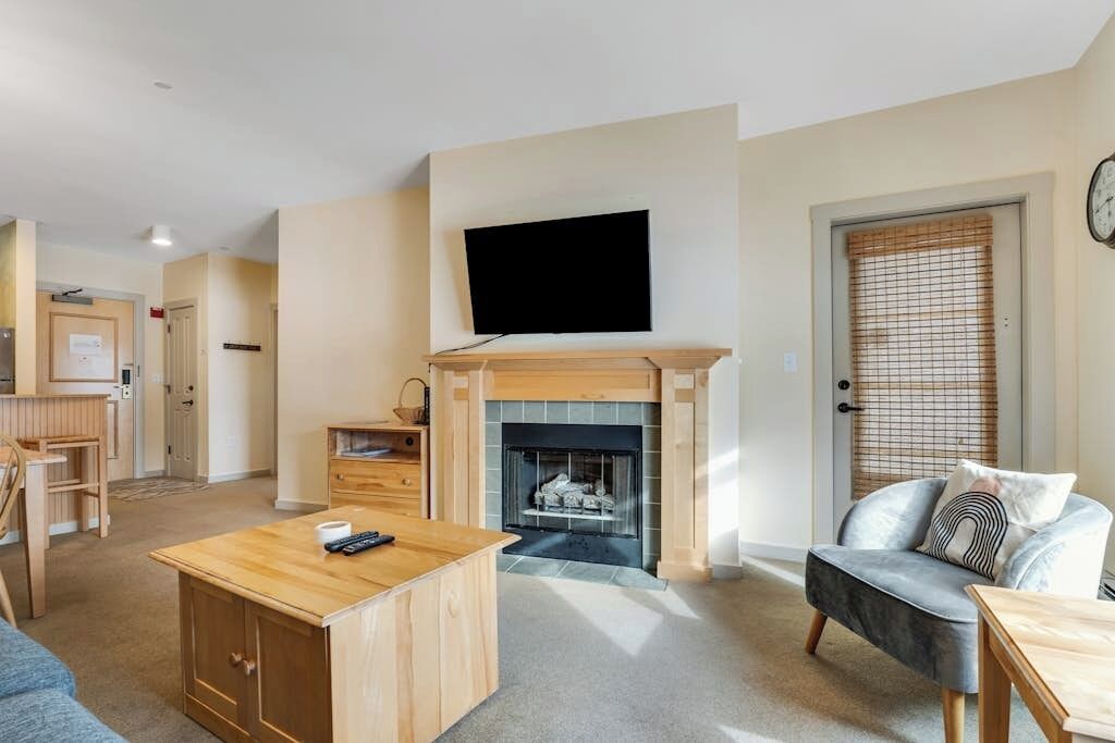 A living room with a fireplace, a television mounted on the wall, a sofa, and a coffee table.