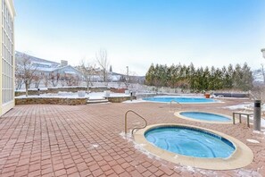 Un área de piscina con dos jacuzzis y un patio de ladrillo.