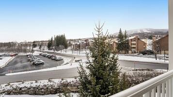 A view of a parking lot with several cars, a stone wall, and buildings in the background.