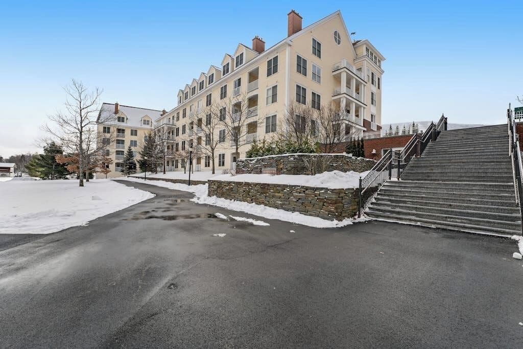 A multi-story building with a stone wall and a staircase leading to the entrance.