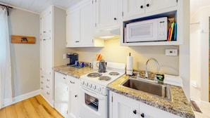 A kitchen with white cabinets, a built-in microwave, a stove, and a sink.