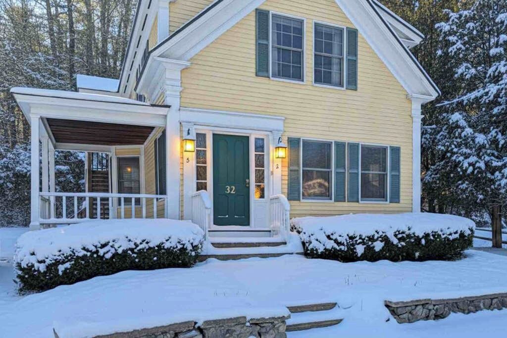 A two-story house with a green door, a porch, and a number '32' on the front.