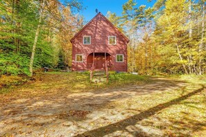 Eine rote Holzhütte mit Veranda, umgeben von Bäumen.