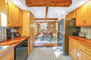 Eine Küche mit Holzausstattung, einem Edelstahlkühlschrank, einem Geschirrspüler sowie einem Essbereich mit Tisch und Stühlen.