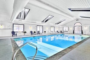 A large indoor swimming pool with a clear view of the ceiling, windows, and seating area. - Inviting condo with a fireplace, hot tubs, pool, tennis & washer/dryer (Ludlow)