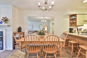 Ein Essbereich mit Holztisch und -stühlen, einer Kandelaber und einer Küche mit Holzschränken und Spüle.