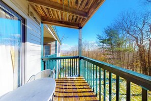 Eine Holzterrasse mit Geländer, Tisch und Stuhl.