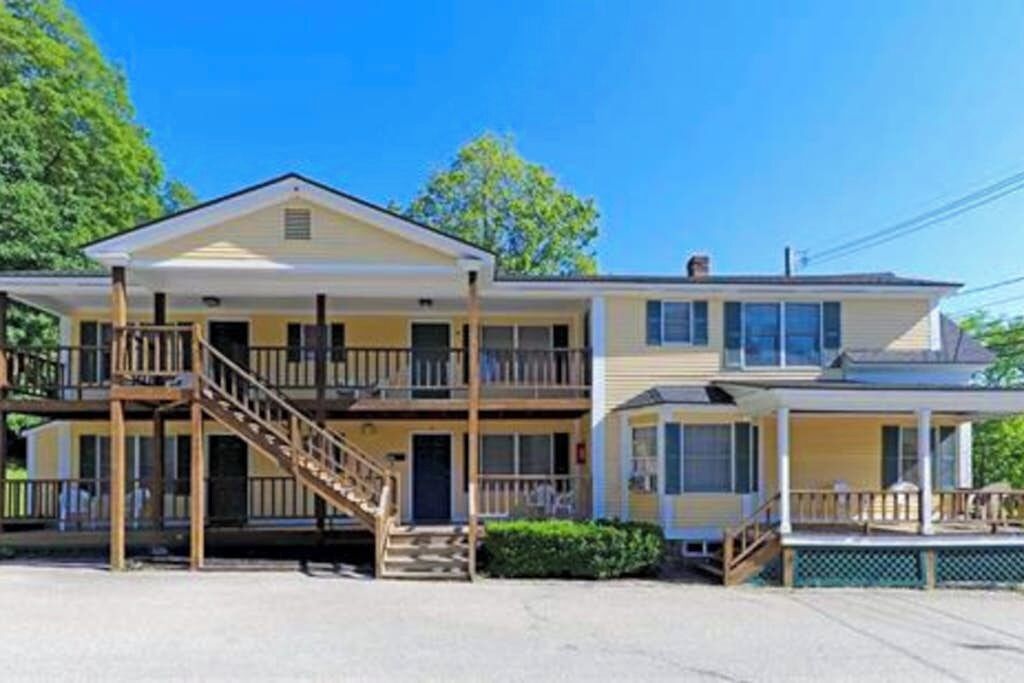 A two-story building with a balcony, a porch, and a staircase leading to the upper level.