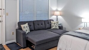 Une chambre moderne avec un canapé-lit, une table de chevet avec une lampe et une porte.