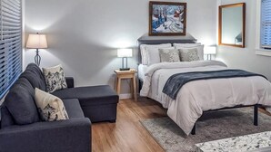 Une chambre à coucher avec un lit, des tables de chevet, un canapé, un tapis et un tableau au mur.