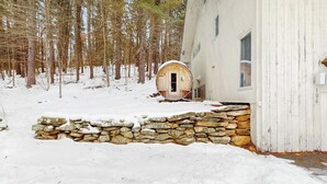 Eine rustikale Holzhütte mit Steineingang, umgeben von einem verschneiten Wald.