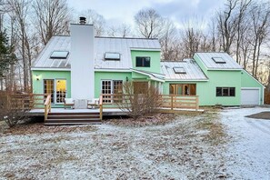 Ein zweistöckiges Haus mit einer Veranda, einem Schornstein und einer Garage.
